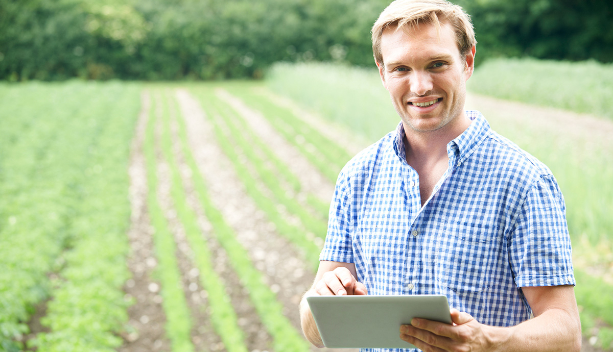 man holding a tablet in front of a field
