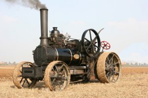 Steam engine with cable pulley system underneath for hauling a plow between engines, cable can be seen to left of front wheels