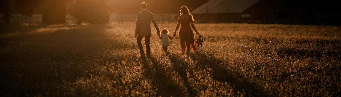 Family family walking through pasture during golden hour