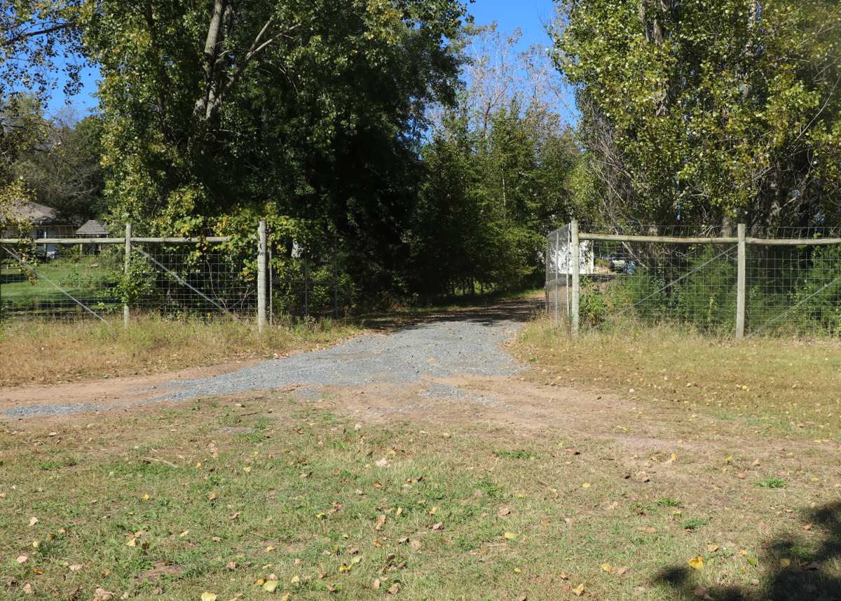 A wide fence opening for a vehicle to access an apple orchard.