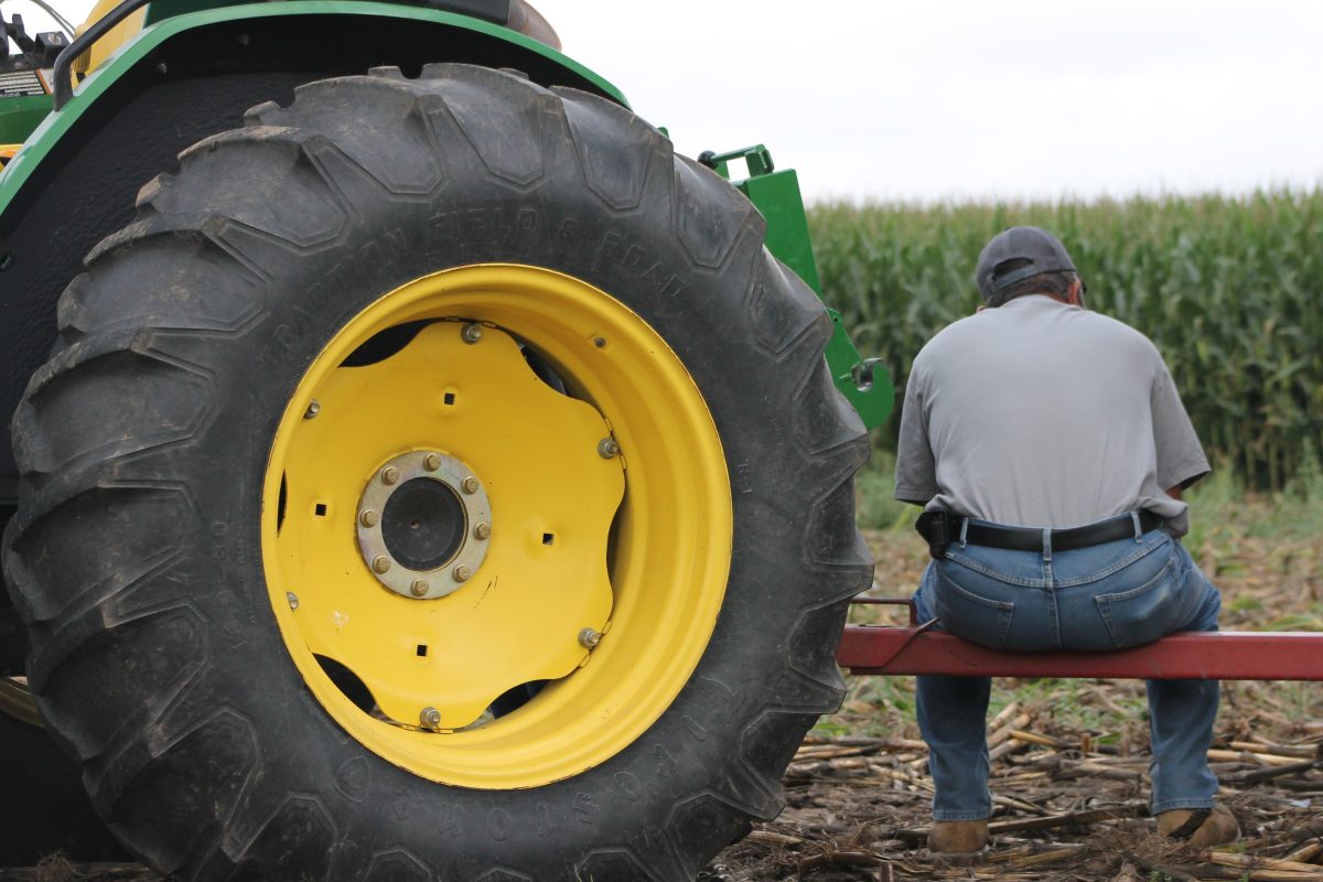 Man sitting next to tractor taking a break